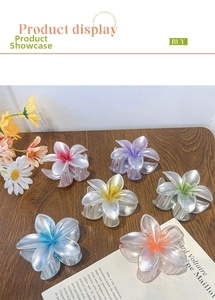 Detailed view of six colorful pearlescent plumeria flower hair clips on a wood surface