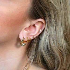 Primo piano di orecchini a cerchio dorati e ear cuff con cristalli sul modello