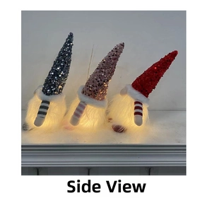 Detail of three sequined Christmas gnomes with warm LED lights on a white shelf