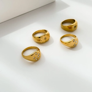 Detailed view of four gold signet rings with starburst engravings and zircon inlays