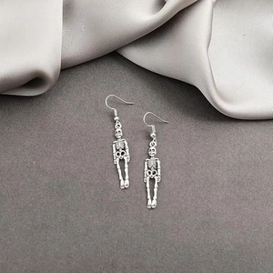 Dettaglio di orecchini pendenti a scheletro argento vintage su sfondo grigio testurizzato