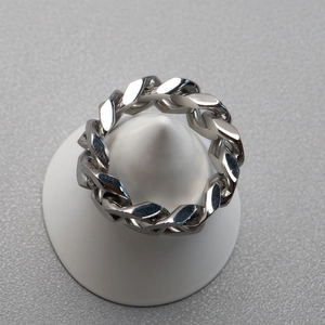 Polished silver cuban link chain ring displayed on a minimalist white conical stand