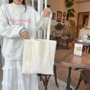 Close-up of intricate floral embroidery and texture on a beige canvas tote bag