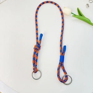 Oranje en blauw gevlochten koord met zilveren metalen ringen op een witte achtergrond