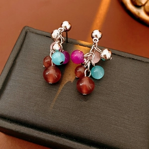 Macro shot of colorful cat eye stone tassel earrings on a premium black textured display