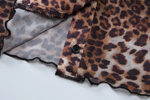 Close-up of leopard print mesh fabric showing lettuce trim hem and sleek black button