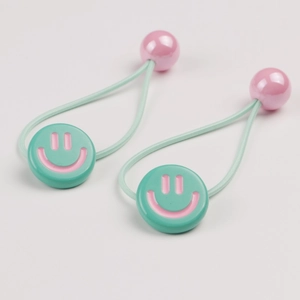 Detail of green elastic hair ties with pink smiley face discs and matching round beads