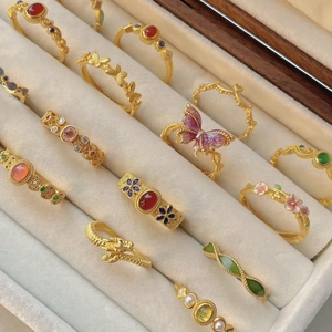 Collection of vintage gold-plated rings with floral and butterfly designs in a jewelry box