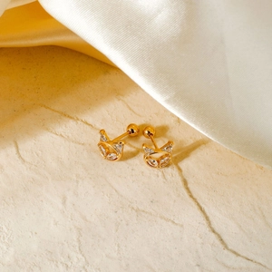 Exquisite gold cat stud earrings with clear cubic zirconia on textured stone background