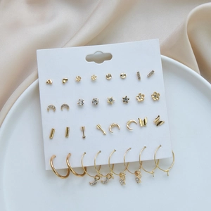 Detail of 16-pair golden geometric earring set with hearts and stars on display card
