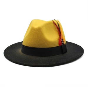 Detail of wool fedora hat featuring yellow crown, black brim, ribbon and feather decor
