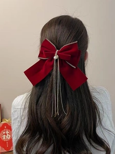Dettaglio del fiocco in velluto rosso con perla e catene di nappe scintillanti