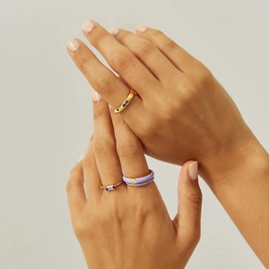Detail of gold stacking rings set with purple stones and lavender enamel finish