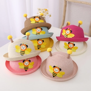 Pile of straw sun hats for children with cute cartoon bee patches and plush antennae