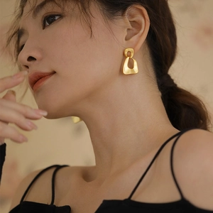 Elegant gold irregular geometric hollow drop earrings worn by model in a retro style