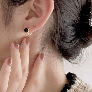 Close-up of elegant black agate earrings with gold plating worn by a model