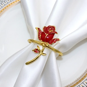 Close-up of a gold napkin ring with a red rhinestone rose on white satin fabric