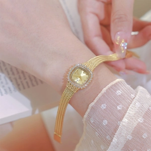 Close-up of women's vintage square gold watch with diamond bezel and woven metal strap
