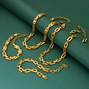 Detail of gold chain necklace with green square gemstones on a matching green stand
