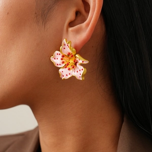 Detailed close-up of a pink enamel flower earring with gold trim worn by a model