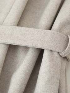 Gros plan du manteau en laine gris clair montrant la texture et la ceinture