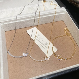 Detail of 18k gold plated butterfly necklaces and bracelet with pearls and zircons