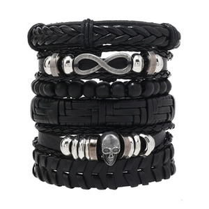Close-up of layered black leather bracelets featuring infinity and skull silver charms