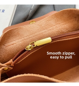 Macro detail of the smooth metal zipper and premium brown leather texture on a tote bag