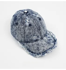 Detail view of washed blue denim baseball cap featuring distressed fringe and frayed edges