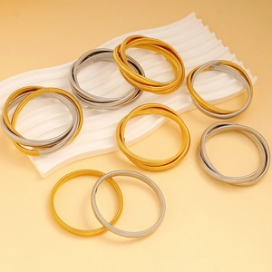 Detailed view of spiral spring cuff bracelets in gold and silver on a wavy display stand