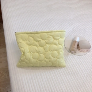 Detailed macro view of yellow quilted makeup bag with embossed floral texture and zipper