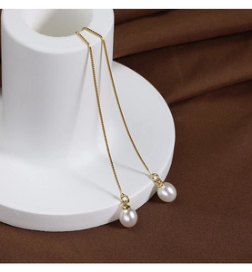 Macro detail of long gold box chain earrings with natural white freshwater pearls