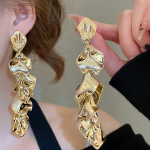 Detail of layered gold geometric floral petal tassel earrings worn by a model
