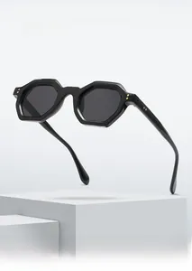 Close-up of black octagonal sunglasses frame with decorative gold rivets on white steps