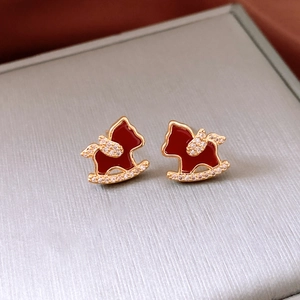 Macro shot of red enamel and 18K gold-plated rocking horse earrings in jewelry box
