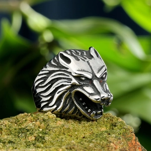 Macro view of vintage silver wolf head ring on mossy rock showing detailed metal texture