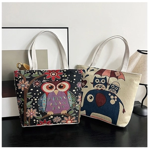 Detail of embroidered canvas tote bags featuring ethnic owl and elephant patterns