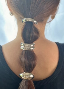 Close-up of minimalist silver metal hair rings styled on a sleek braided hairstyle