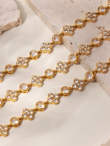Macro view of 18k gold plated bracelet with cubic zirconia clover and round charm links