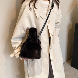 Sac seau en peluche noire avec bandoulière en cuir porté sur un trench-coat beige