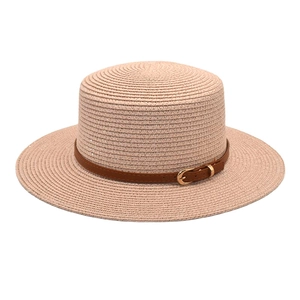 Close-up of pink woven straw flat top hat featuring a brown faux leather buckle strap