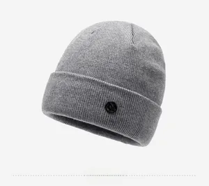 Detail view of the gray knitted beanie showing textured fabric and black circular badge