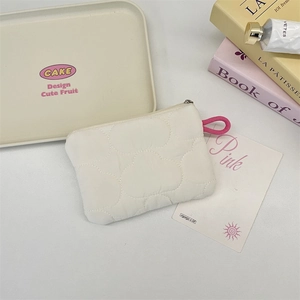 Close-up of white quilted cloud coin pouch with pink strap and metal zipper detail