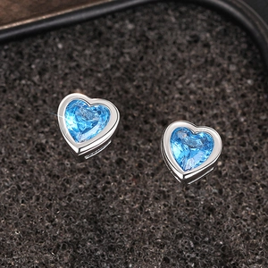 Macro shot of silver heart earrings with bright blue stones in bezel setting