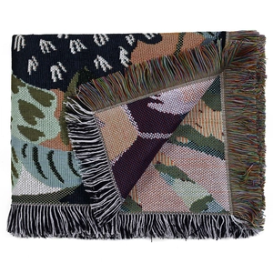 Detail of bohemian woven blanket featuring multi-color jacquard patterns and long fringes