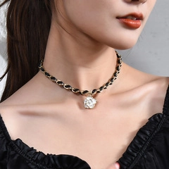Close-up of elegant gold woven chain featuring a white camellia flower pendant on model