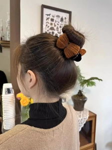 Close-up of a brown knit bow hair claw clip styling a bun on a woman from behind