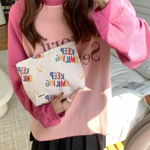 Detailed close-up of white corduroy pouch with colorful Keep Smiling text and smiley prints