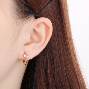 Close-up of a pink heart-shaped gemstone earring in gold on a female ear model