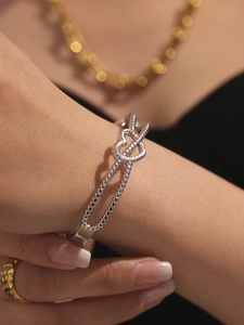 Gros plan d'un bracelet en acier inoxydable argenté avec double cœur et perles sur le poignet